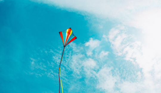 rainbow kite flying against blue sky